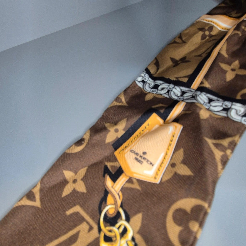 Motif imprimé Louis Vuitton avec étiquette graphique et chaîne dorée sur fond Monogram